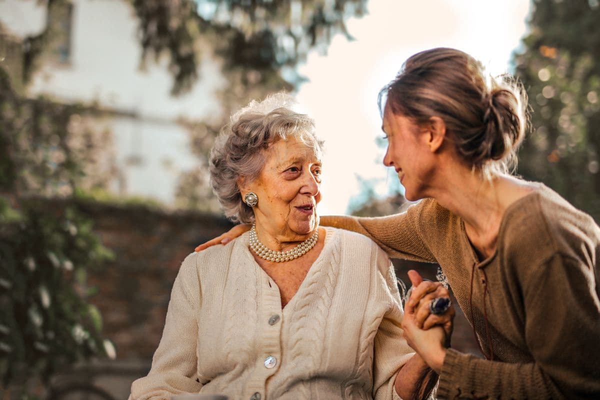 A younger woman walking outdoors beside an older woman